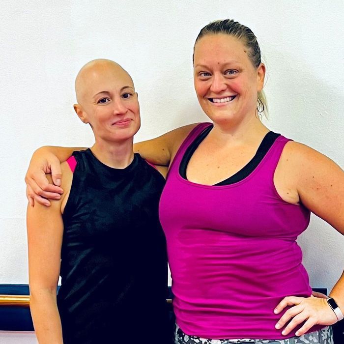 Two women posing for a picture with one wearing a pink tank top.