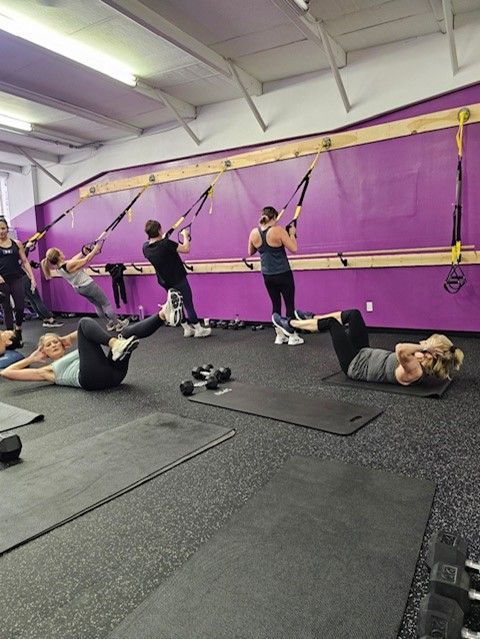 A group of people are doing exercises in a gym.