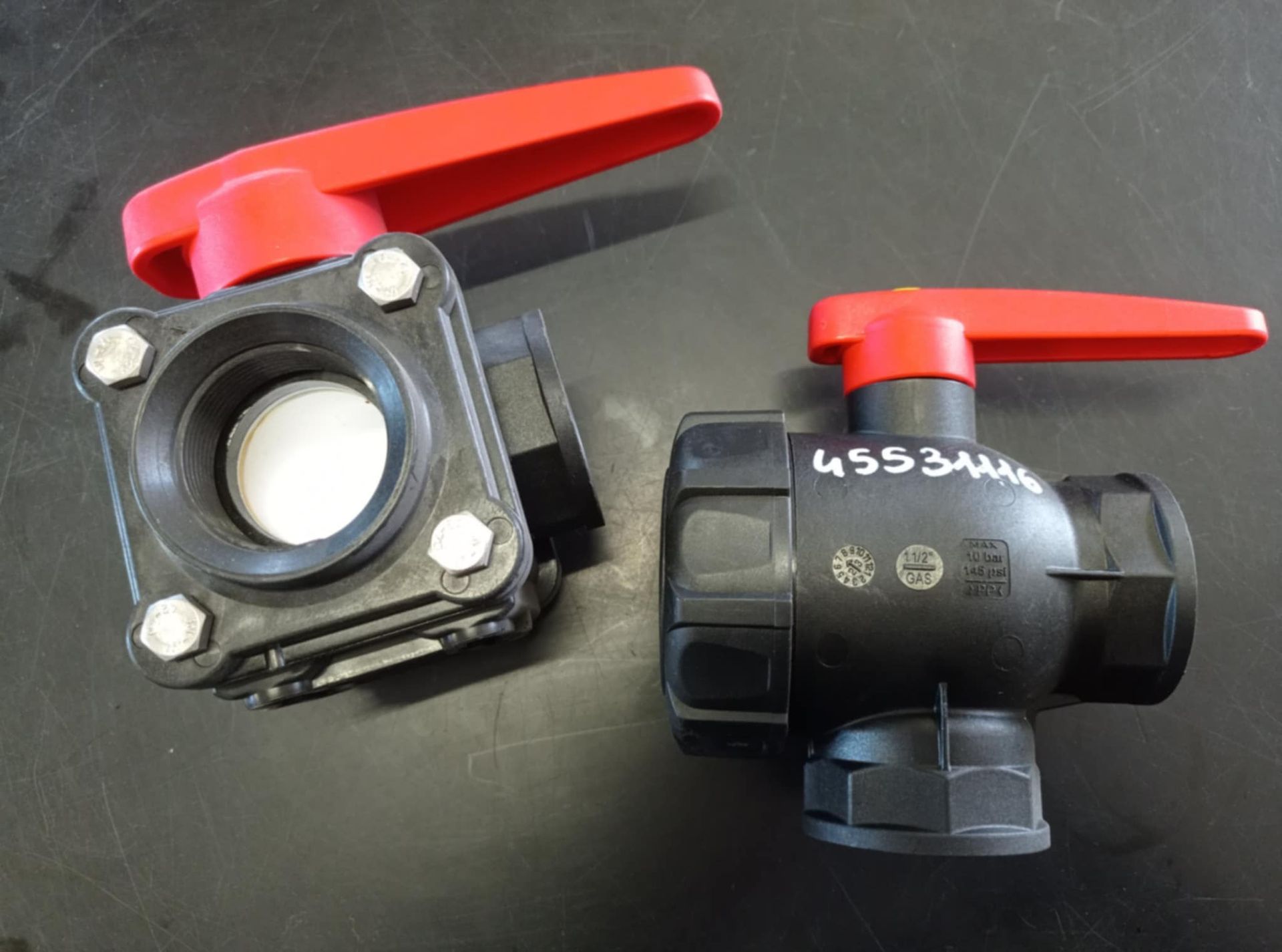 Due valvole a sfera con maniglie rosse su una superficie nera