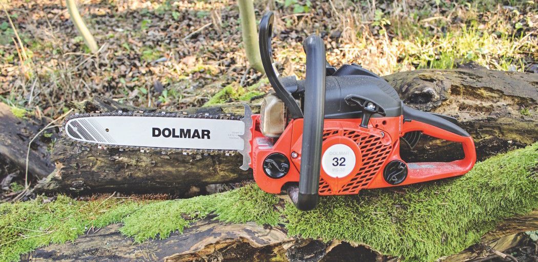 Una motosega è appoggiata su un tronco muschioso nel bosco.