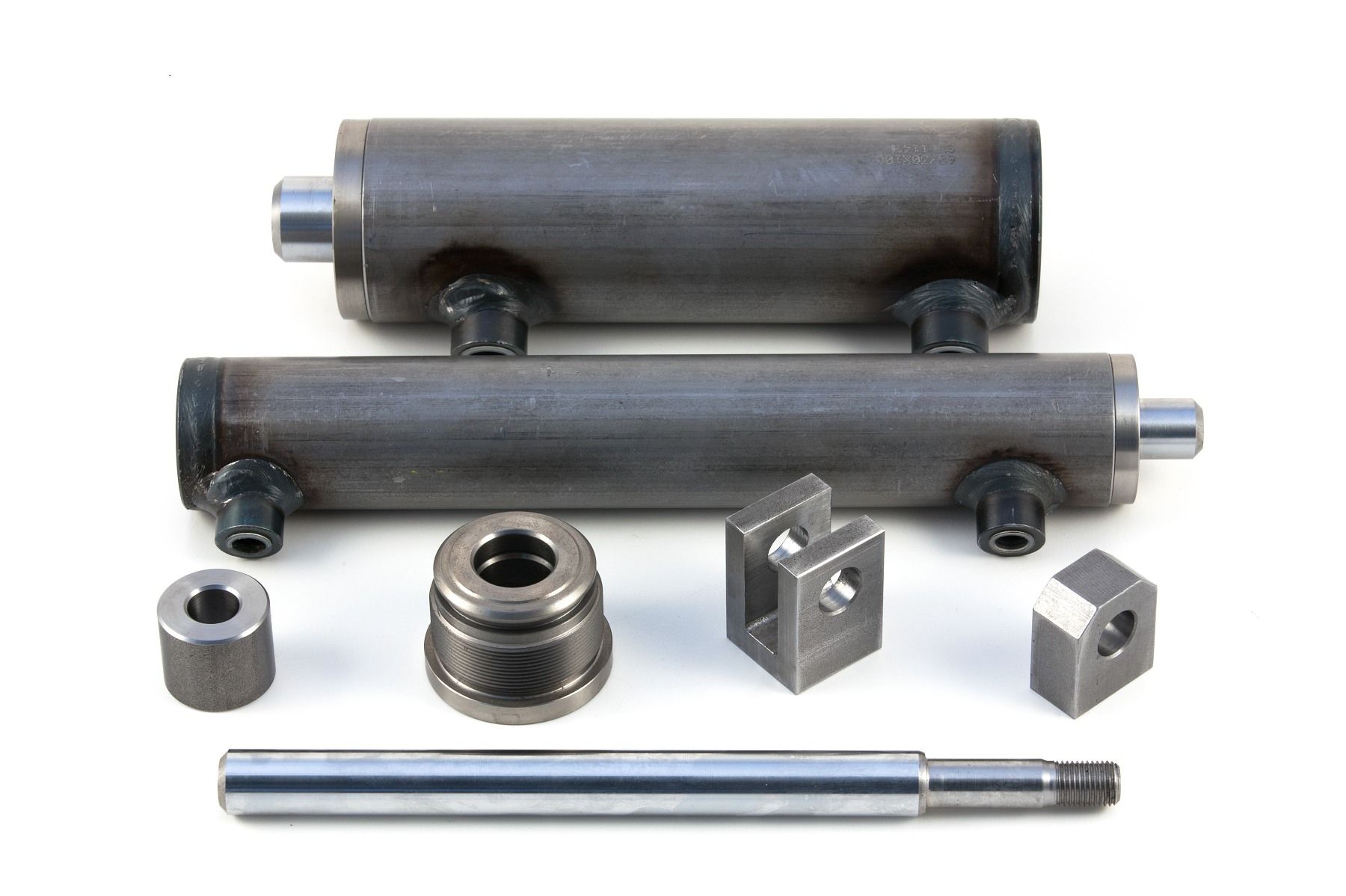 Un mucchio di cilindri e parti di metallo su una superficie bianca