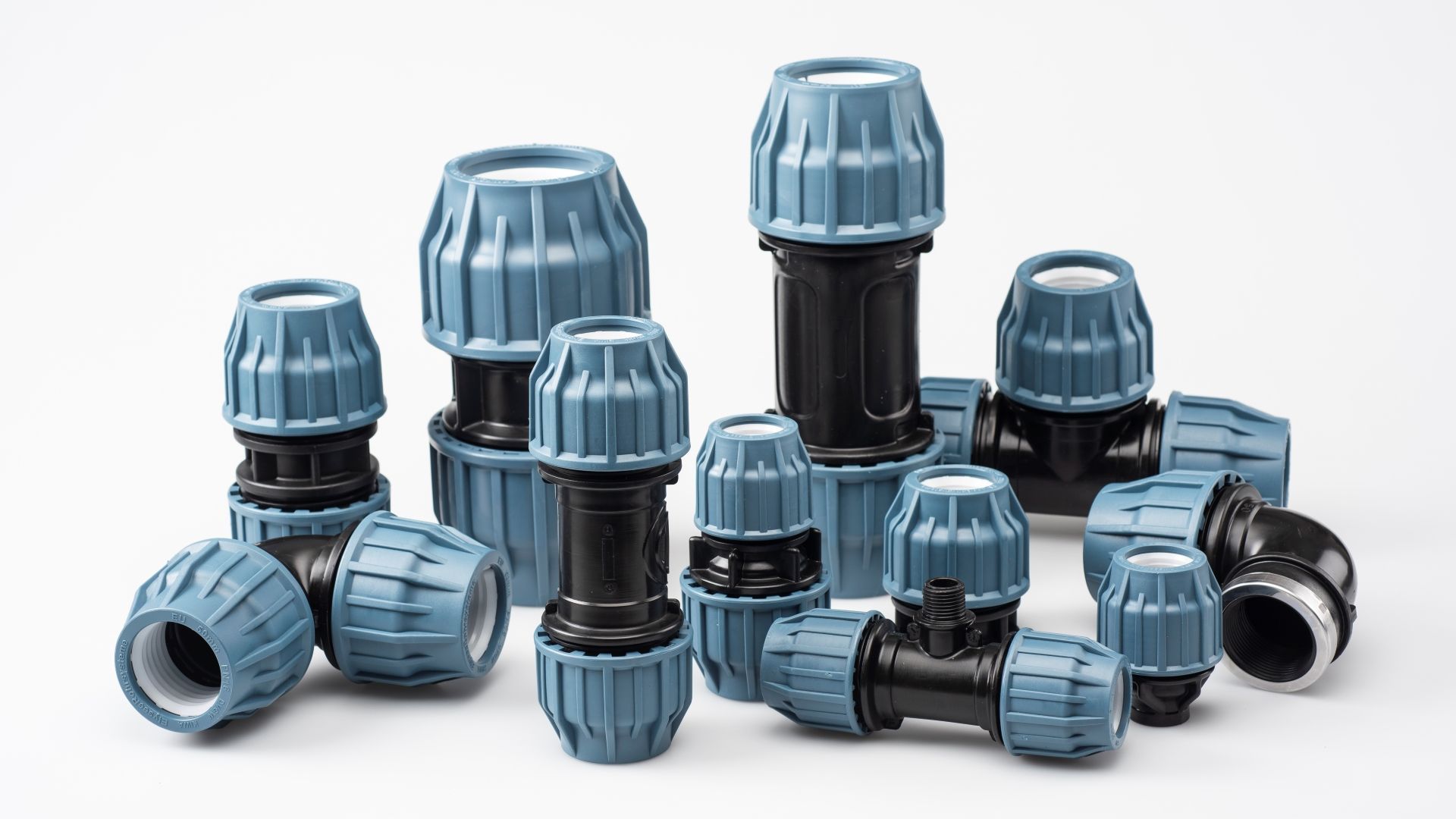 Un mucchio di raccordi per tubi di plastica sono appoggiati uno sopra l'altro su una superficie bianca.