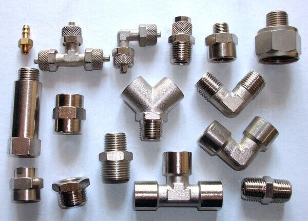 Un mucchio di raccordi in ottone su una superficie bianca