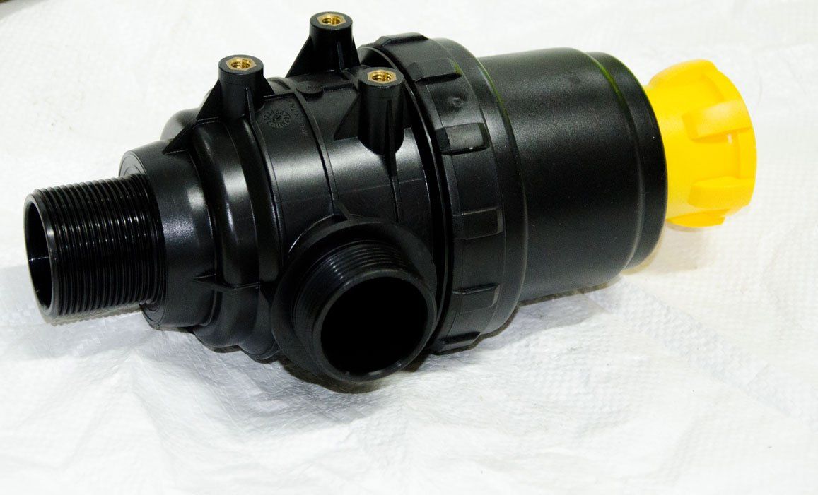 Una valvola di plastica nera con un tappo giallo è appoggiata su una superficie bianca.