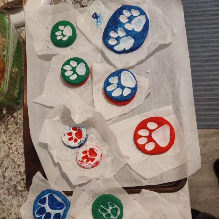 Painted rocks with paw prints on parchment paper.