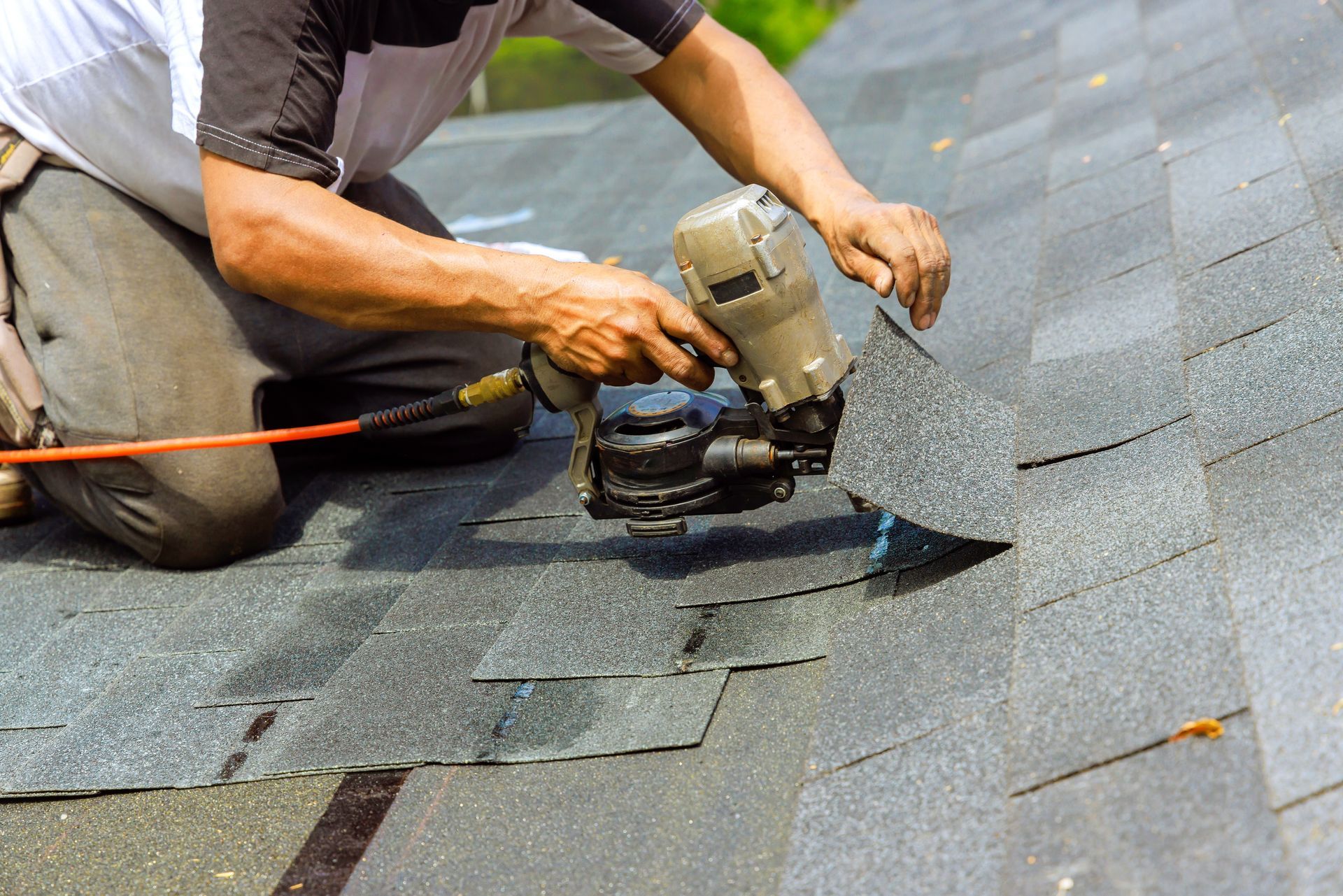 Worker using a power saw to cut roofing shingles on a roof