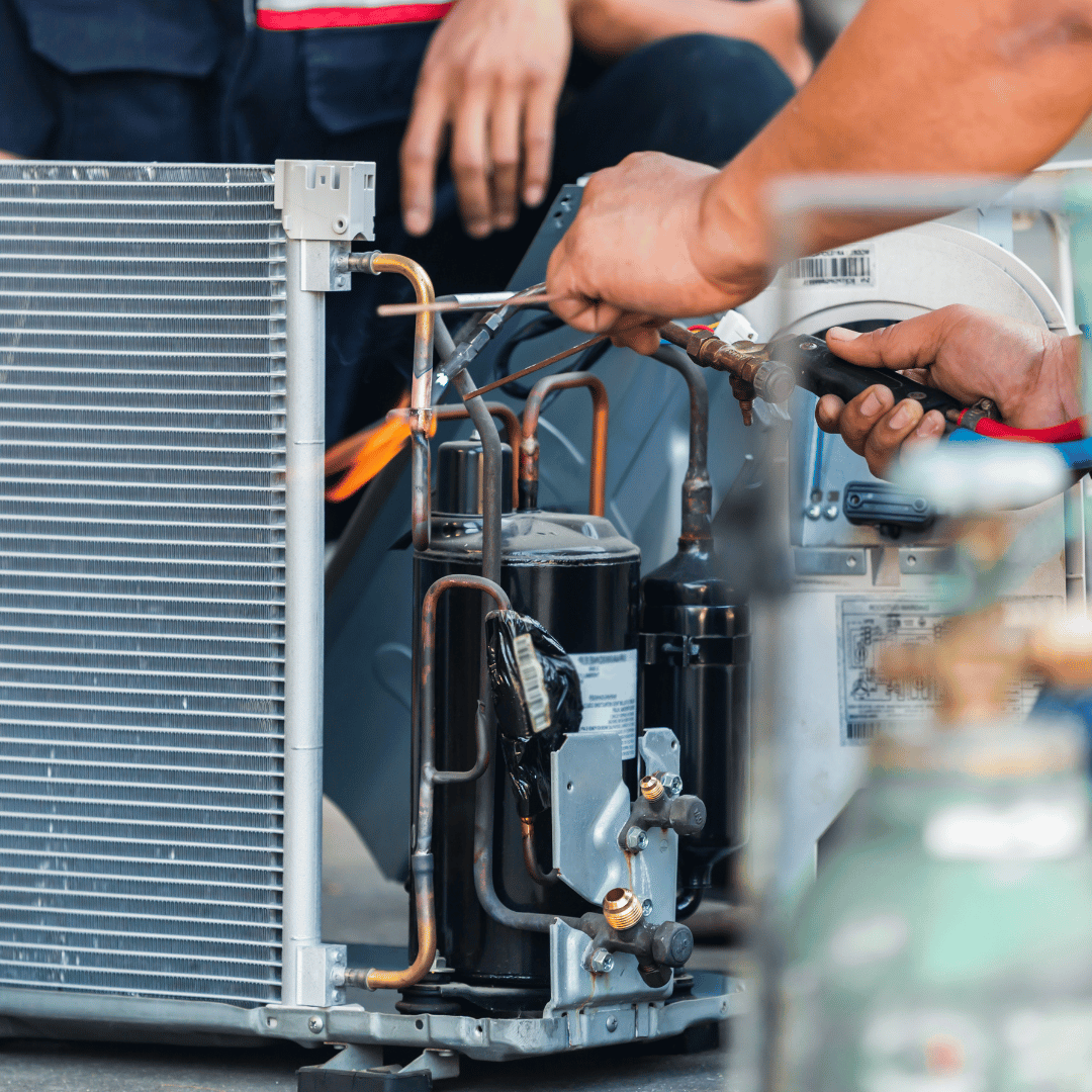A man is working on an air conditioner with a screwdriver.