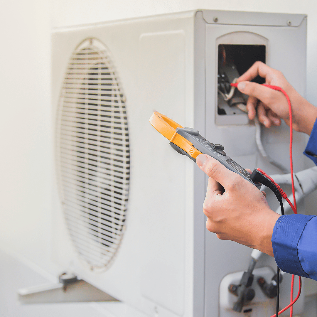A person is working on an air conditioner with a clamp.
