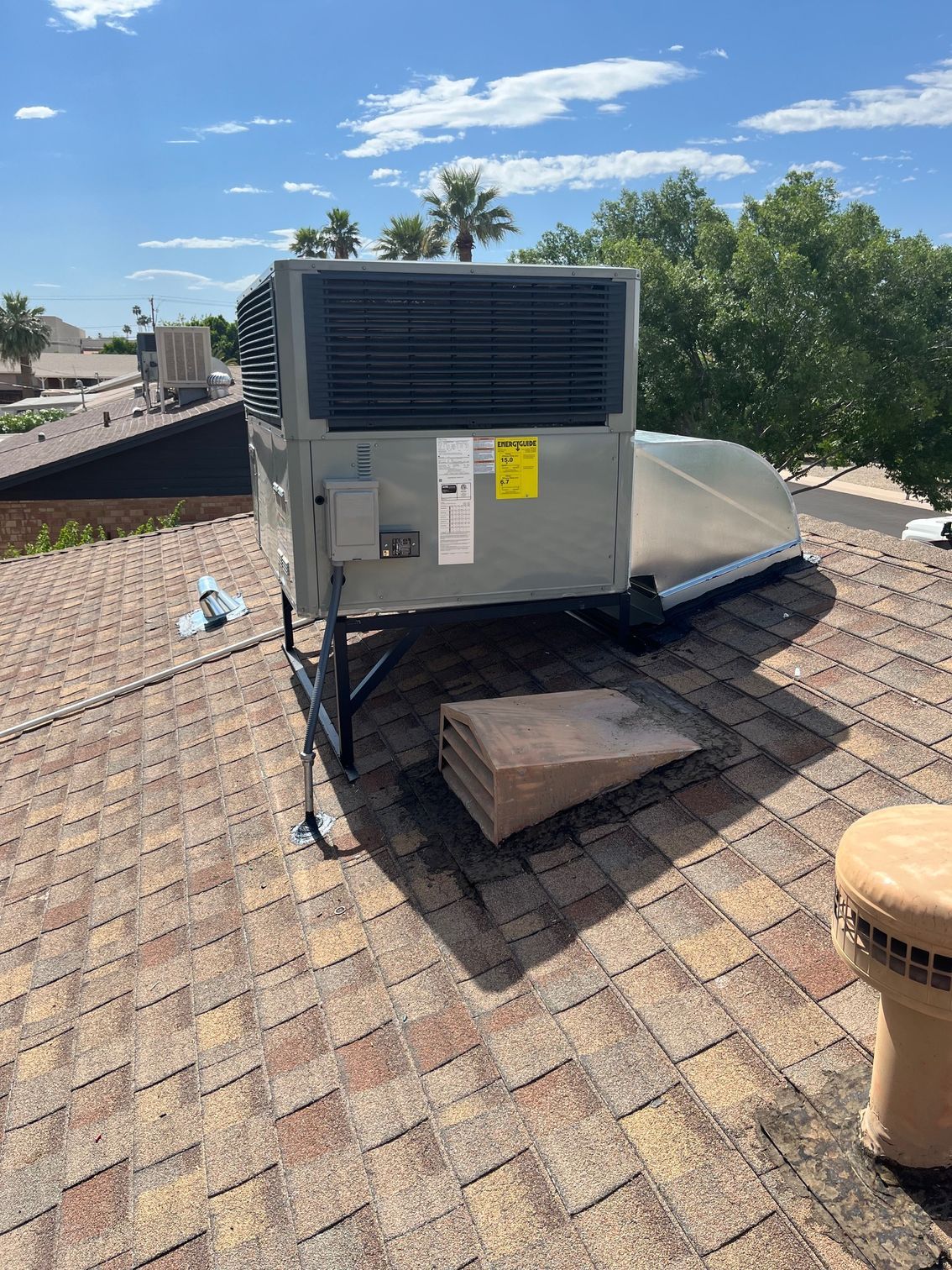 A large air conditioner is sitting on top of a brick roof.