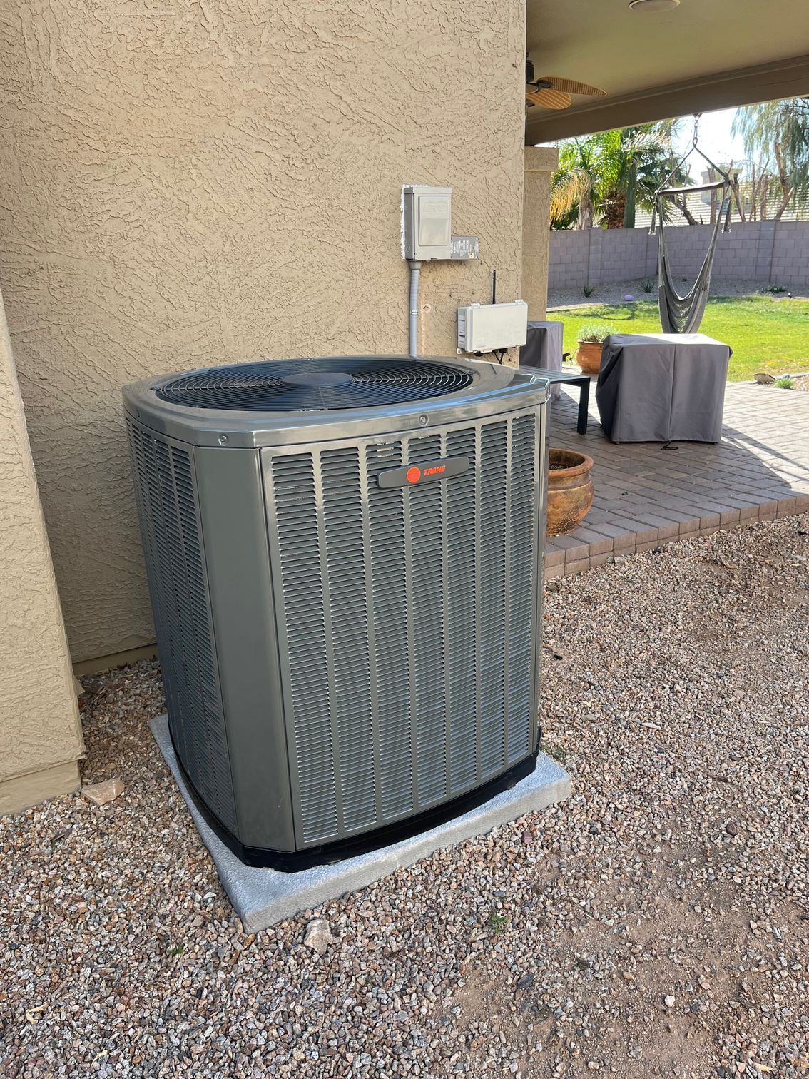 A large air conditioner is sitting outside of a house.