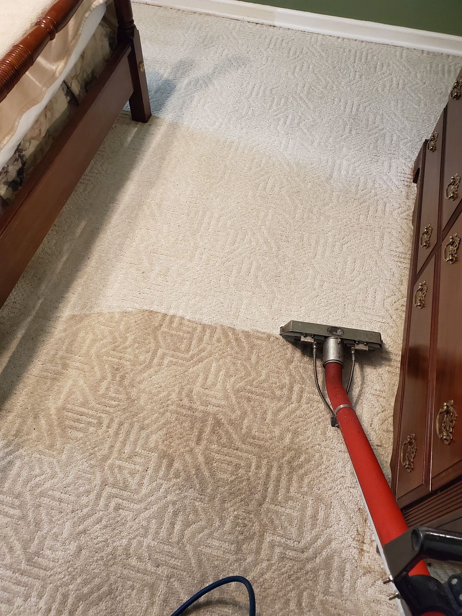 A vacuum cleaner is being used to clean a carpet in a bedroom.