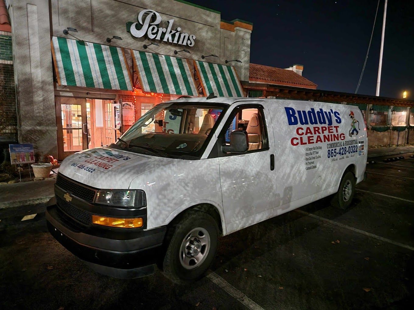 A white van is parked in front of a building that says buddy 's carpet cleaning.