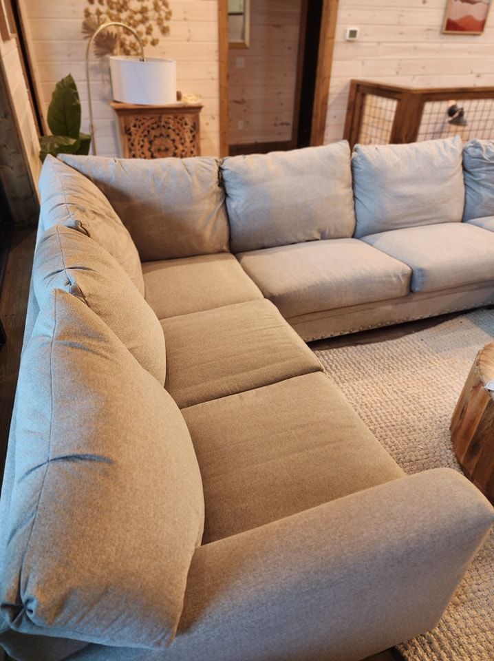 A large sectional couch is sitting in a living room next to a wooden table.