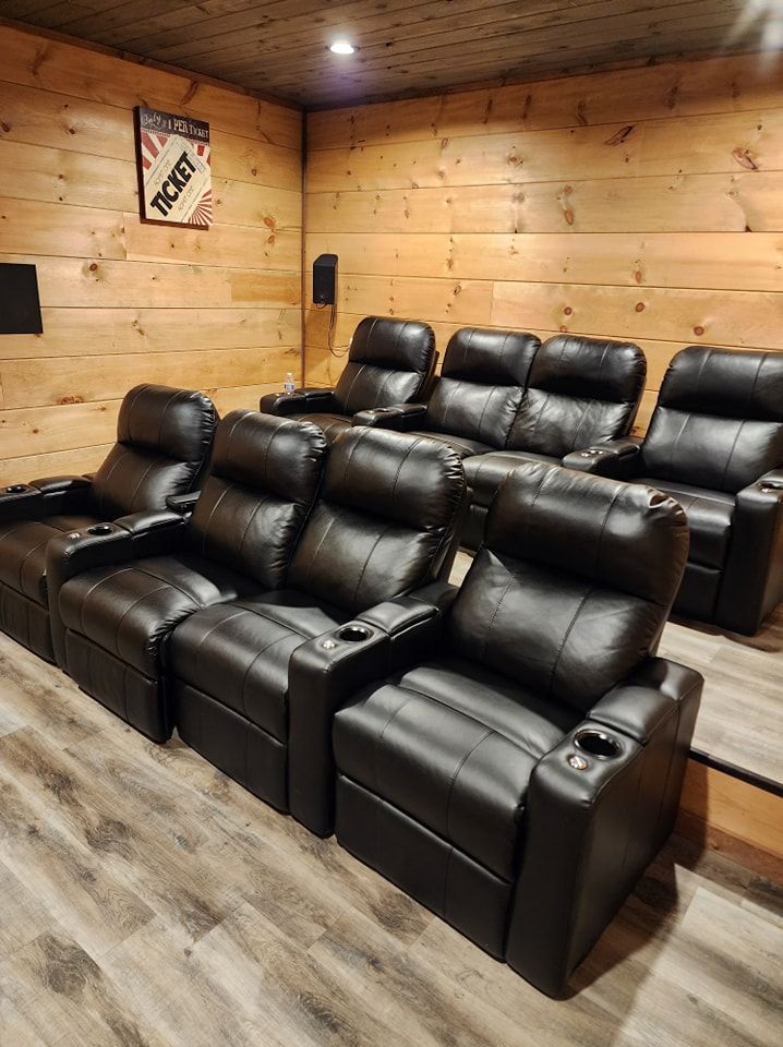 A row of black leather recliner chairs in a home theater.