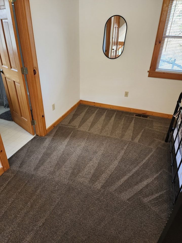 A bedroom with a carpeted floor and a mirror on the wall.