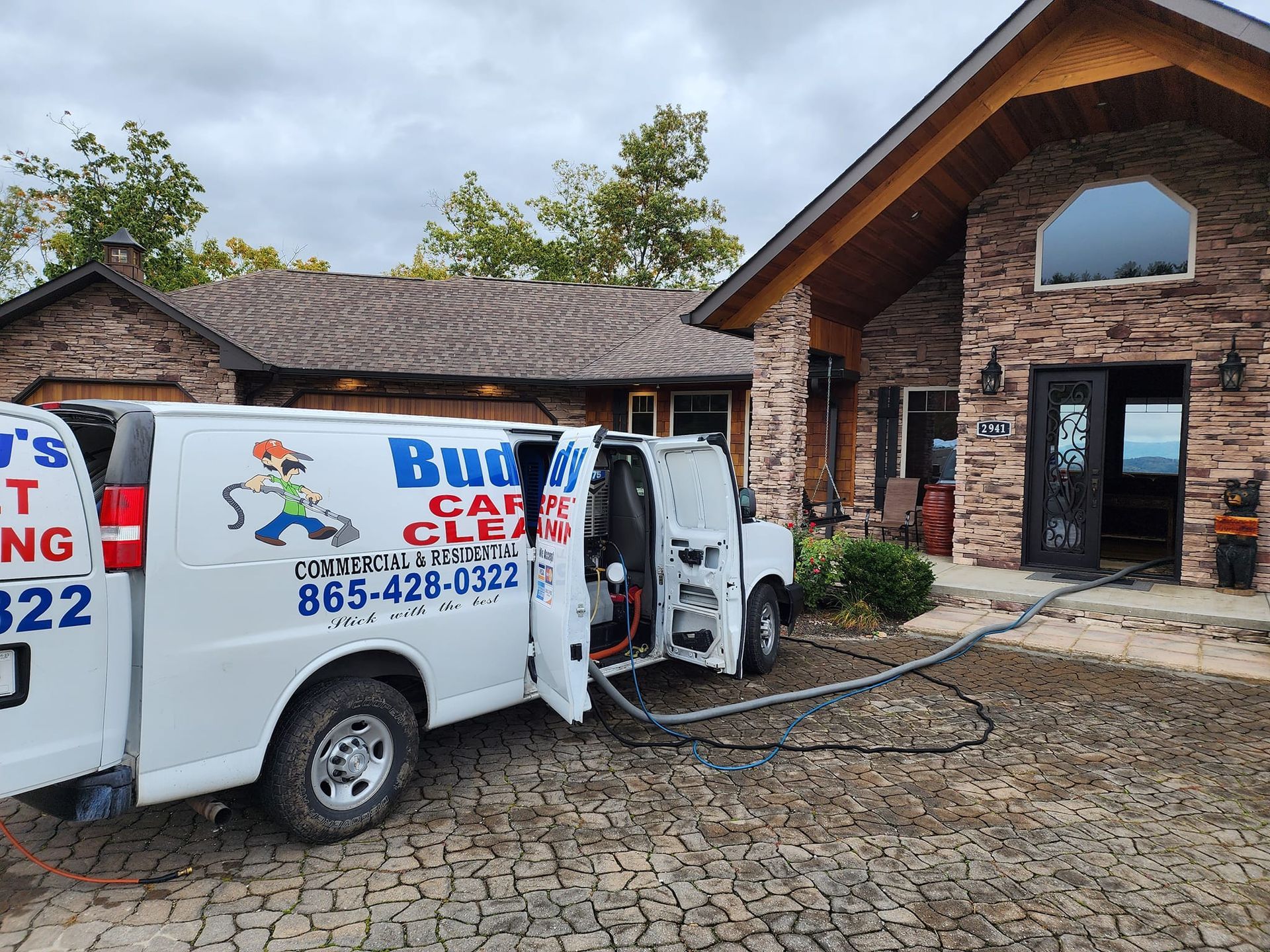A white van is parked in front of a brick house.