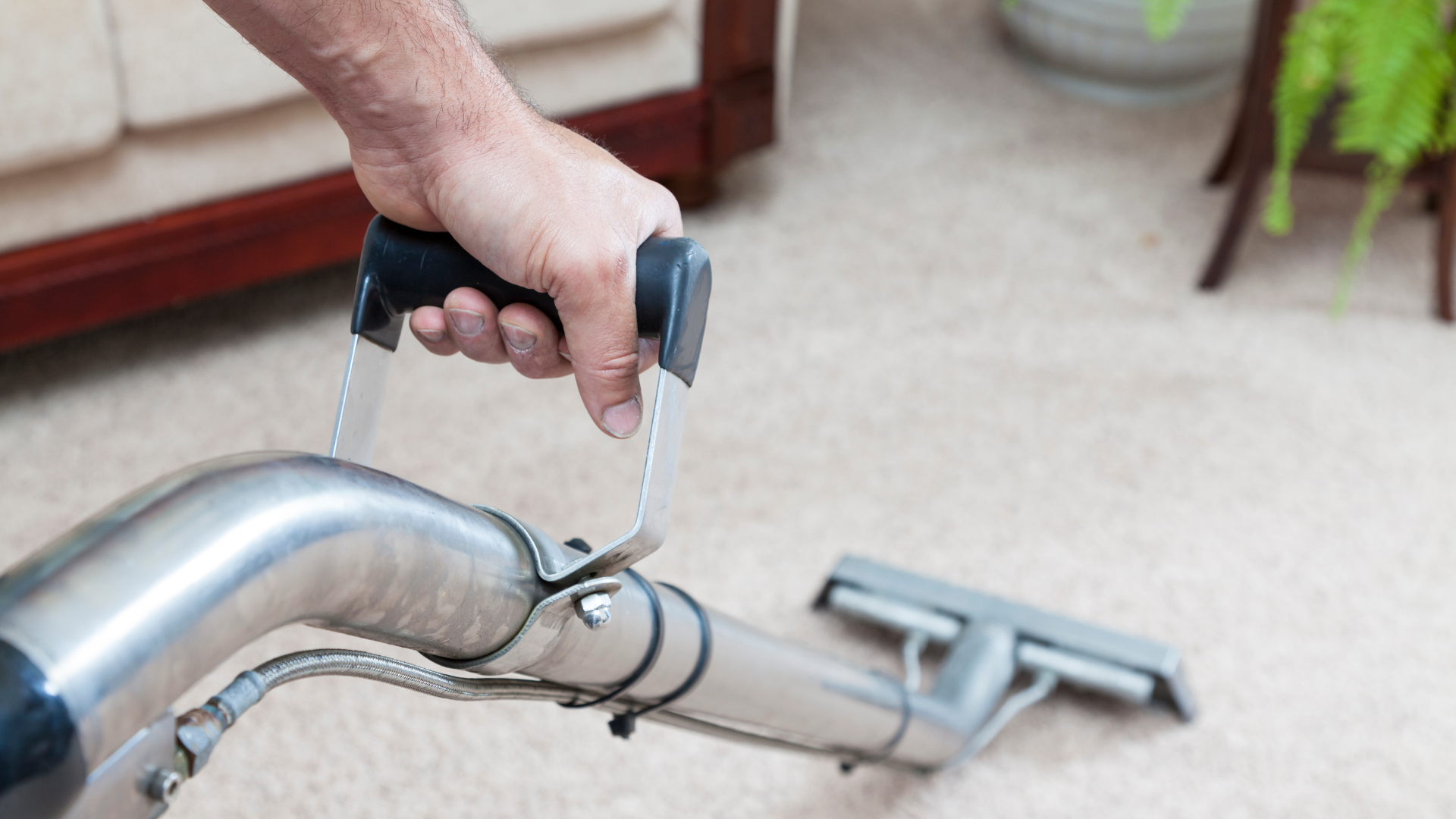A person is using a vacuum cleaner to clean a carpet in a living room.
