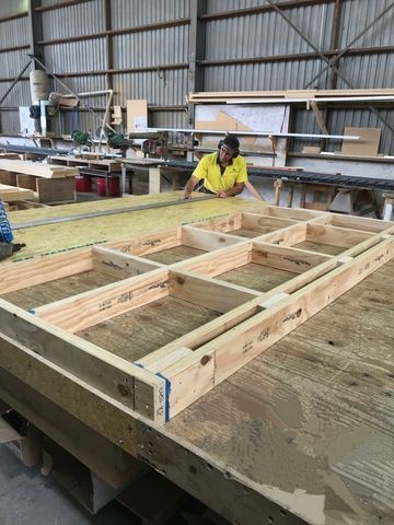 A man is working on a wooden structure in a warehouse.