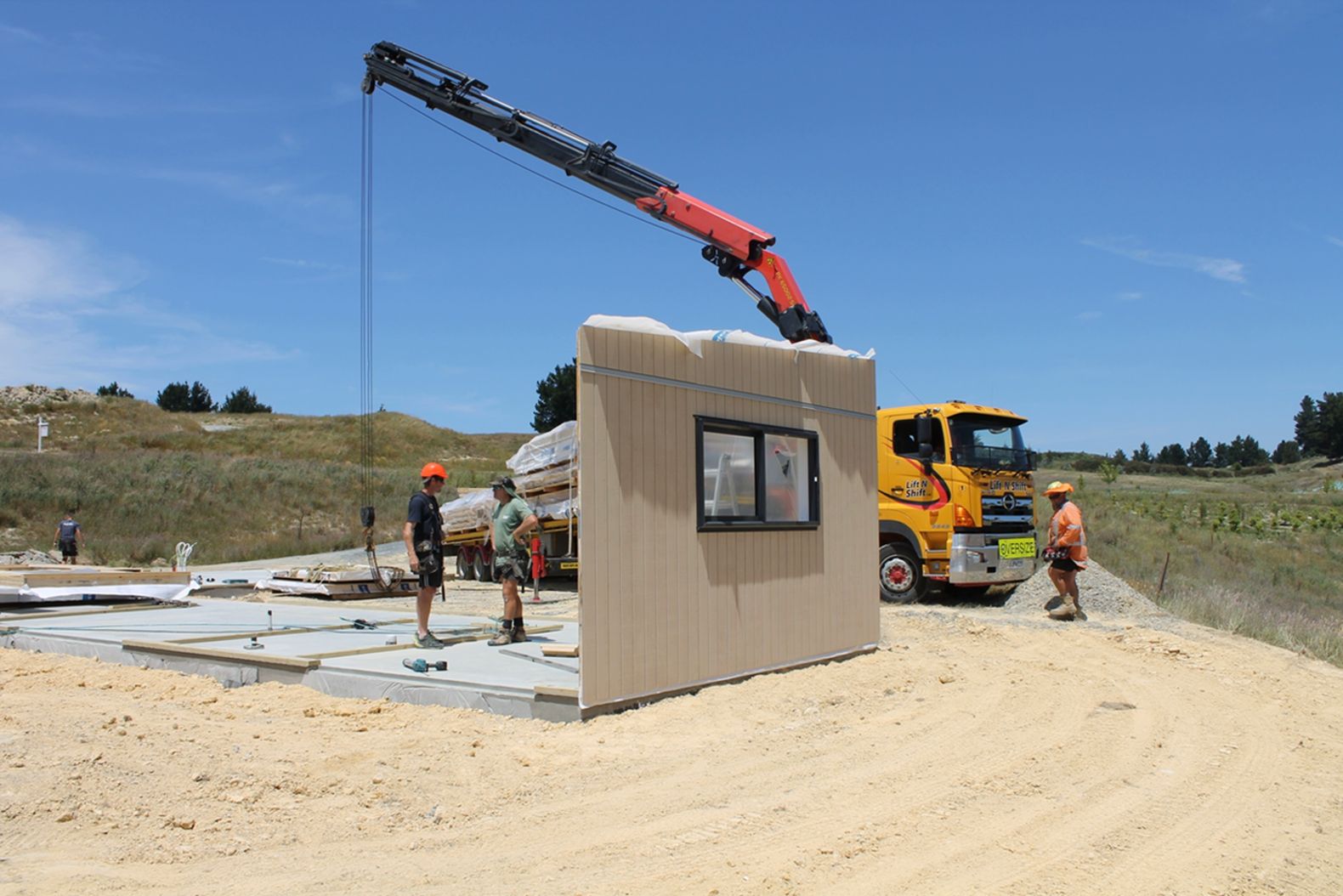 A crane is lifting a wall on a construction site.