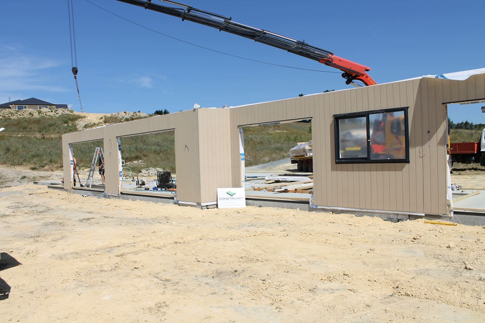 A crane is lifting a wall in a construction site