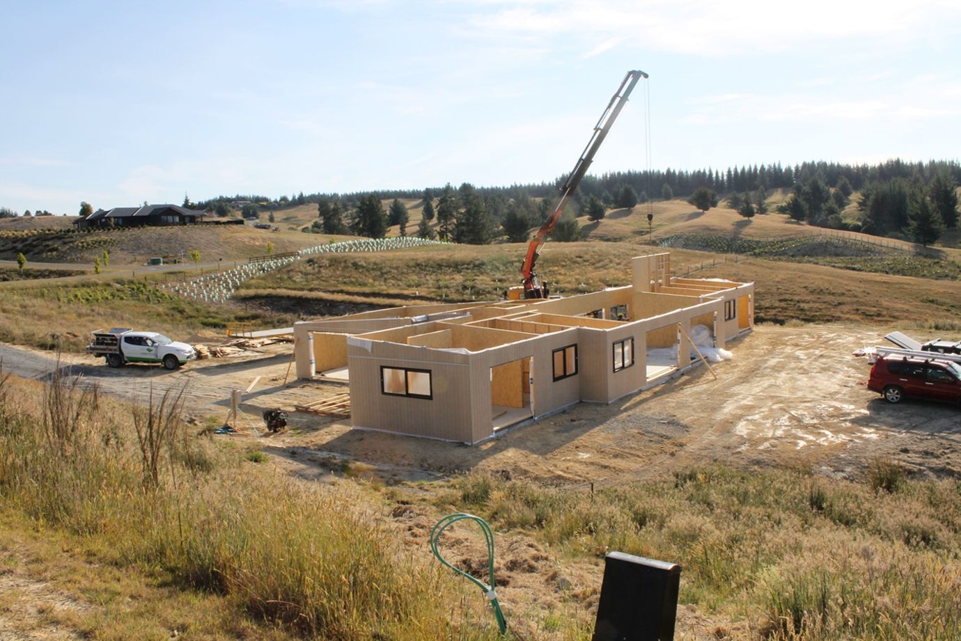 A large house is being built in a field with a crane.