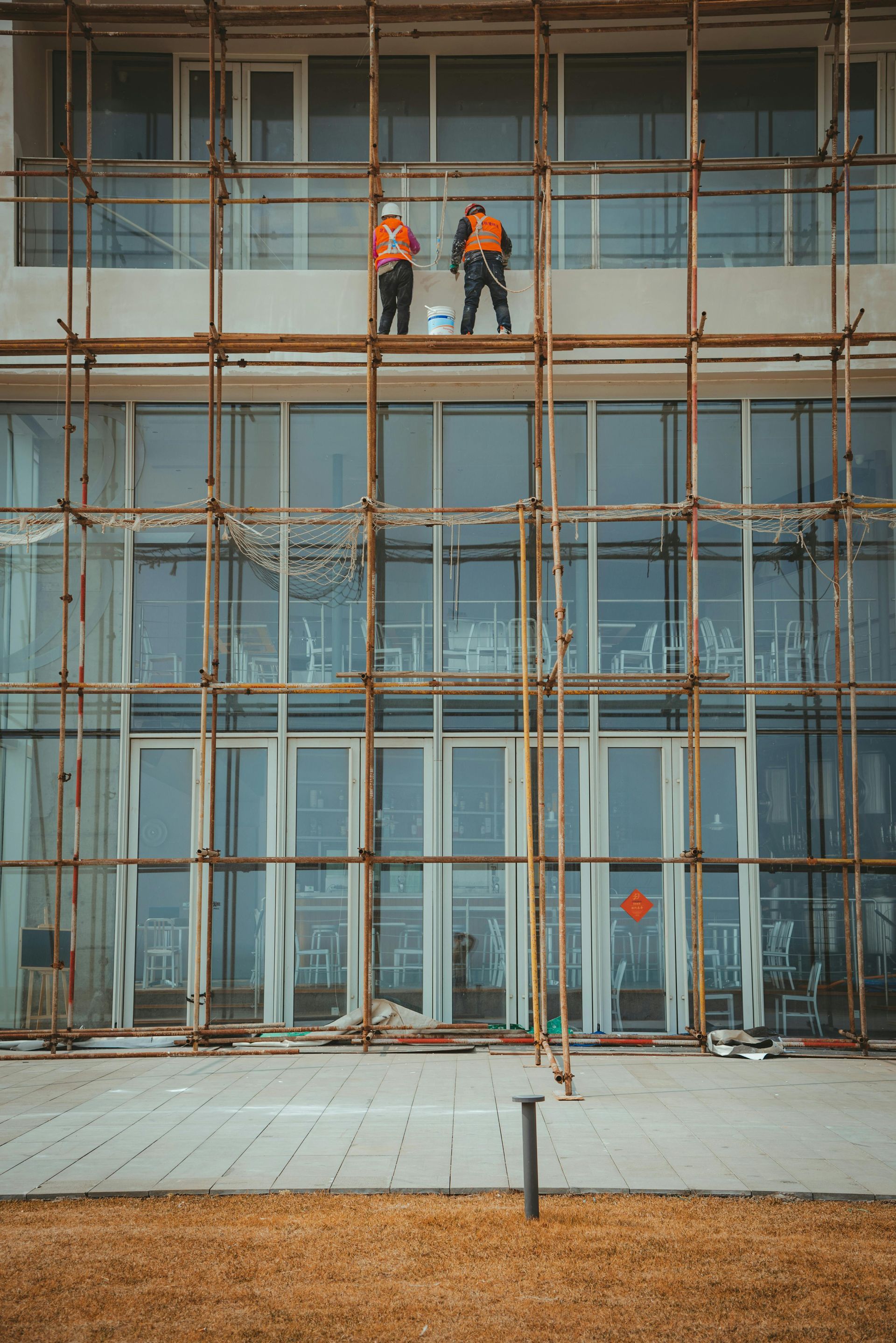Two construction workers are standing on top of a building under construction.