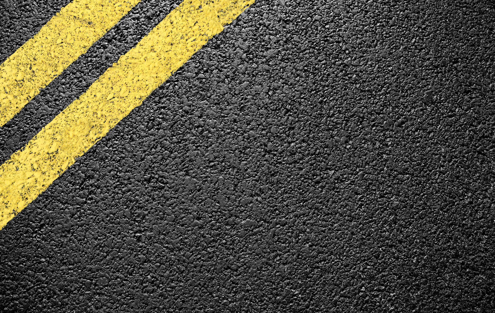 Close up of black asphalt with yellow markings showcasing commercial paving contractor services.