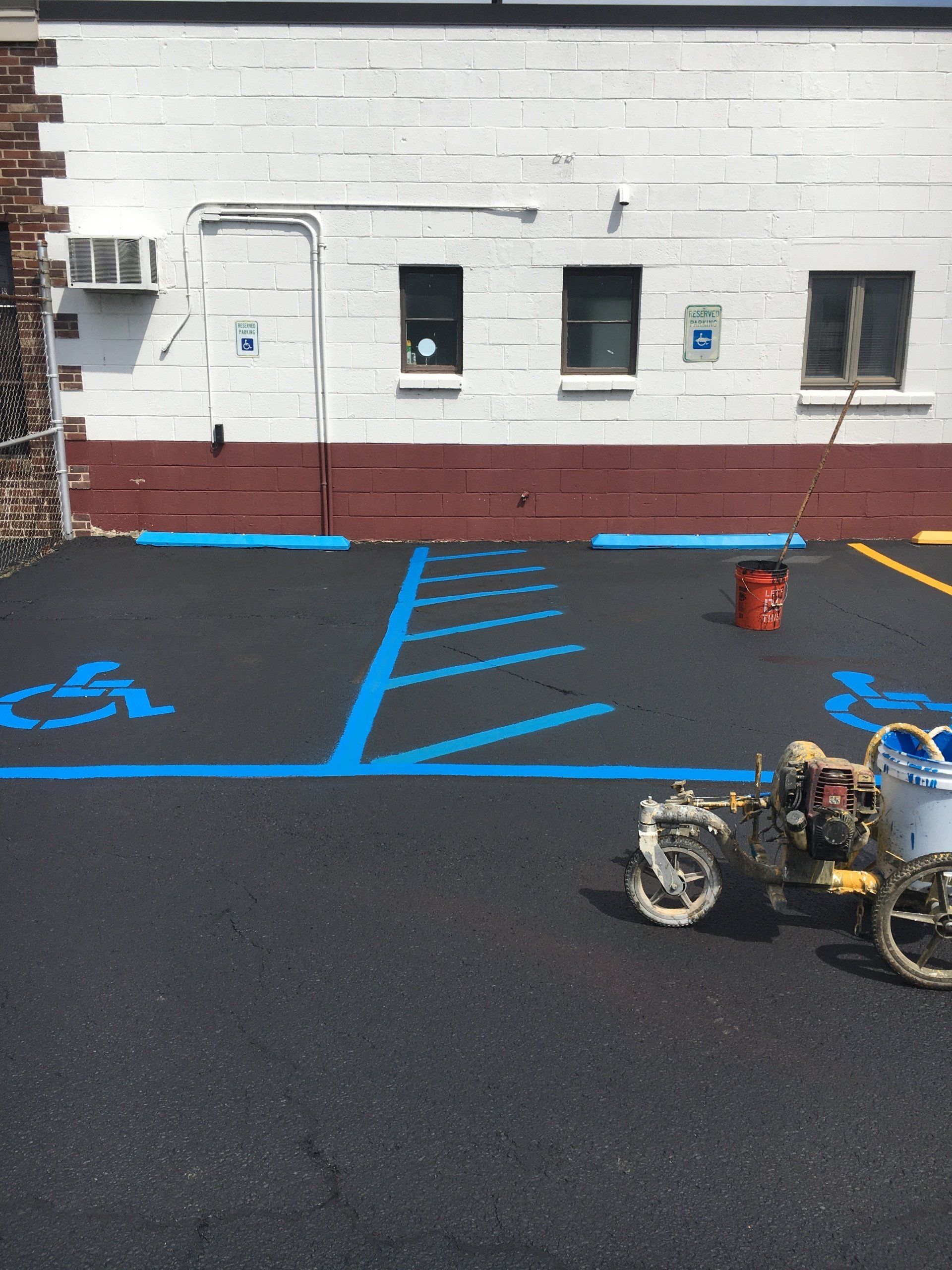 Parking lot with new blue handicap markings being painted.