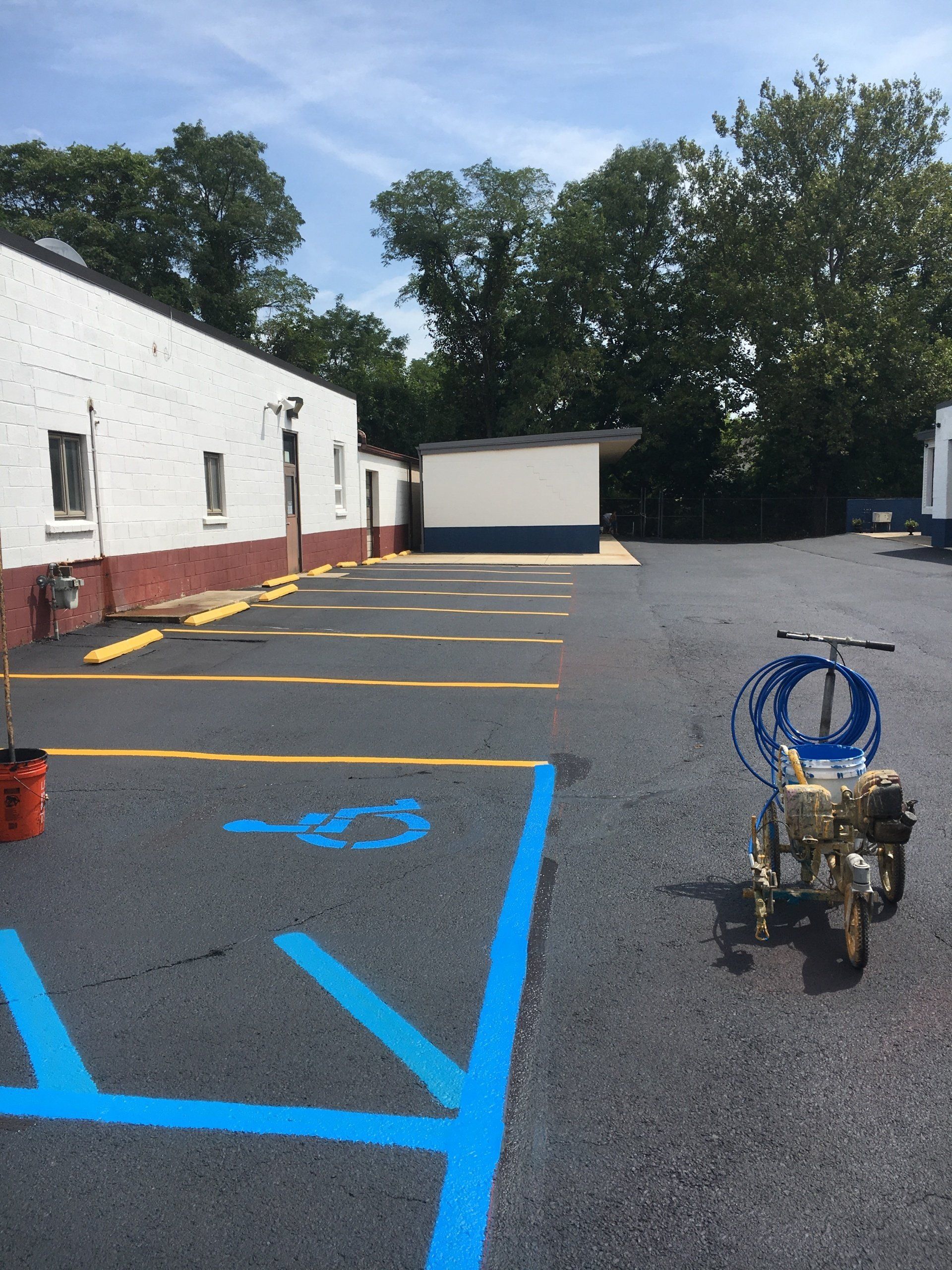Newly paved parking lot with blue handicap space markings and yellow parking lines.