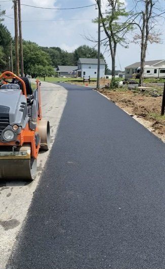 Road paving in progress; a new asphalt road with a roller on the left.