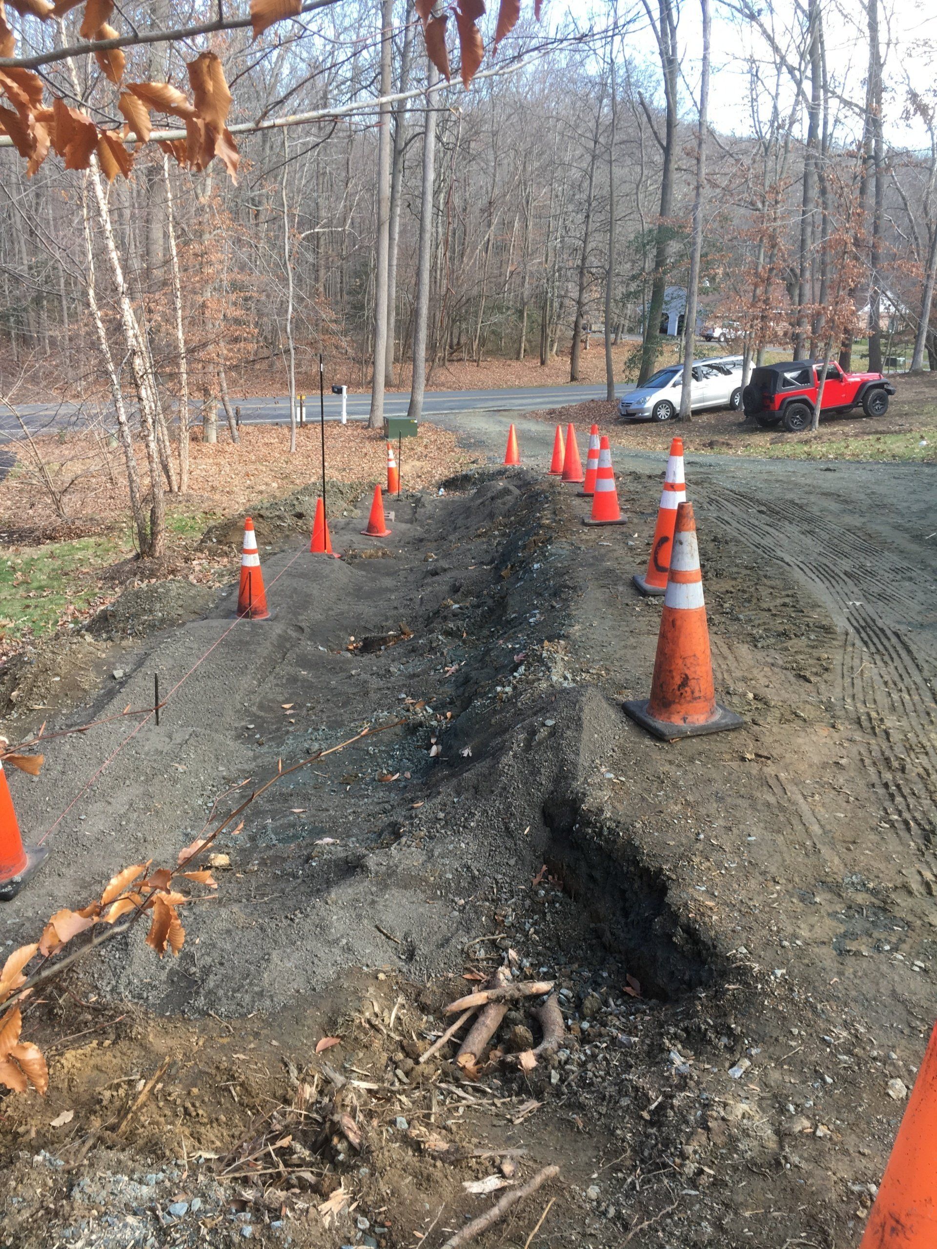 Construction zone on a dirt road, marked by orange traffic cones.