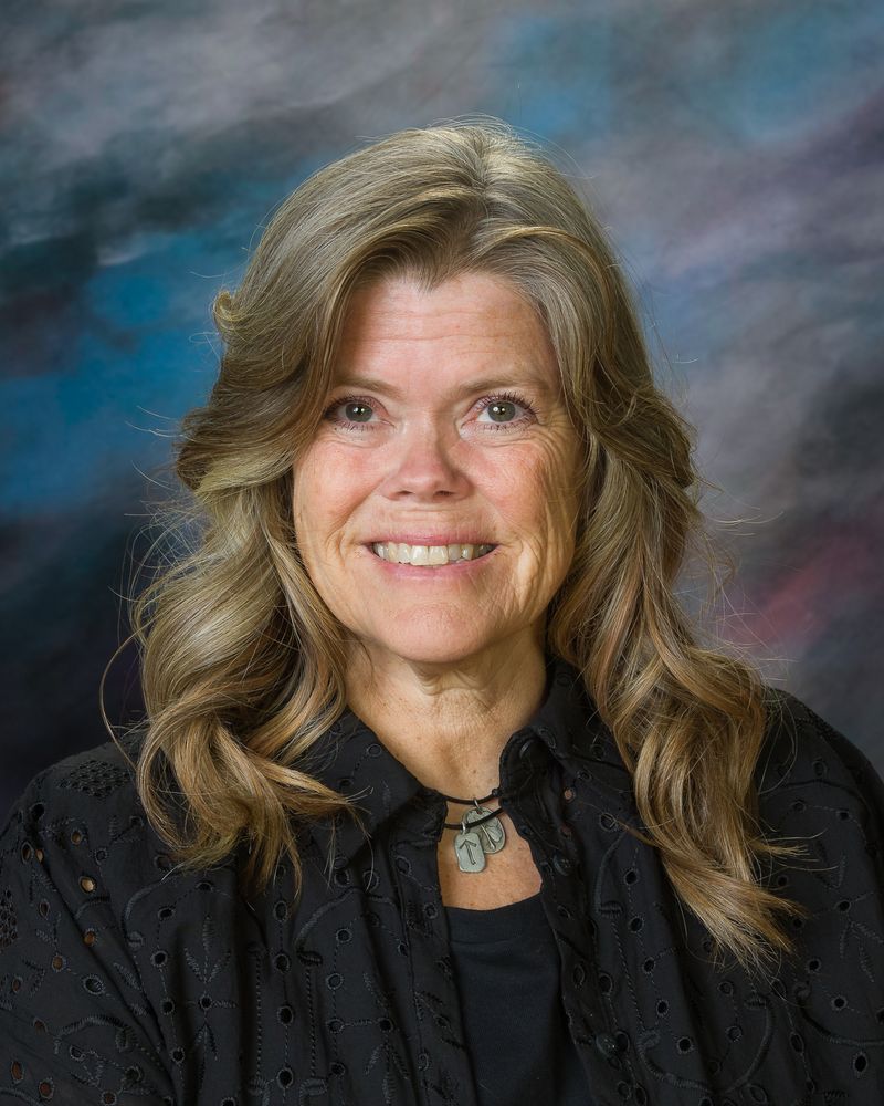 A woman in a black shirt and necklace is smiling for the camera.