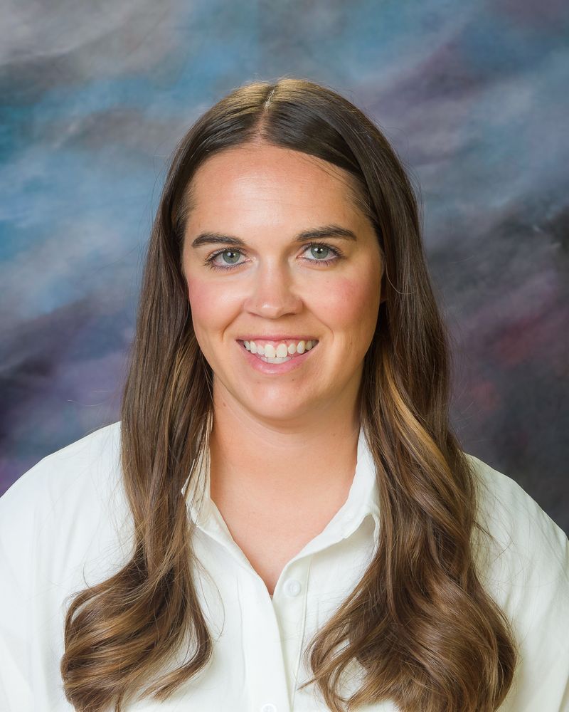 The woman is wearing a white shirt and smiling for the camera.
