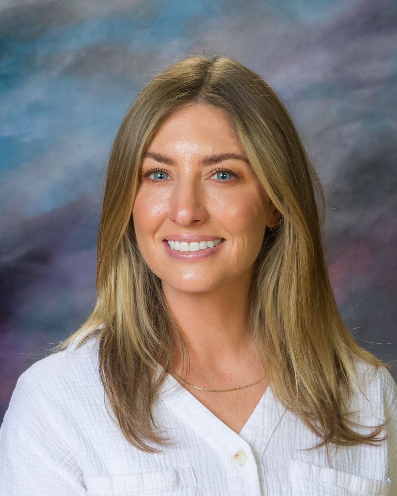 A woman in a white shirt is smiling for the camera.