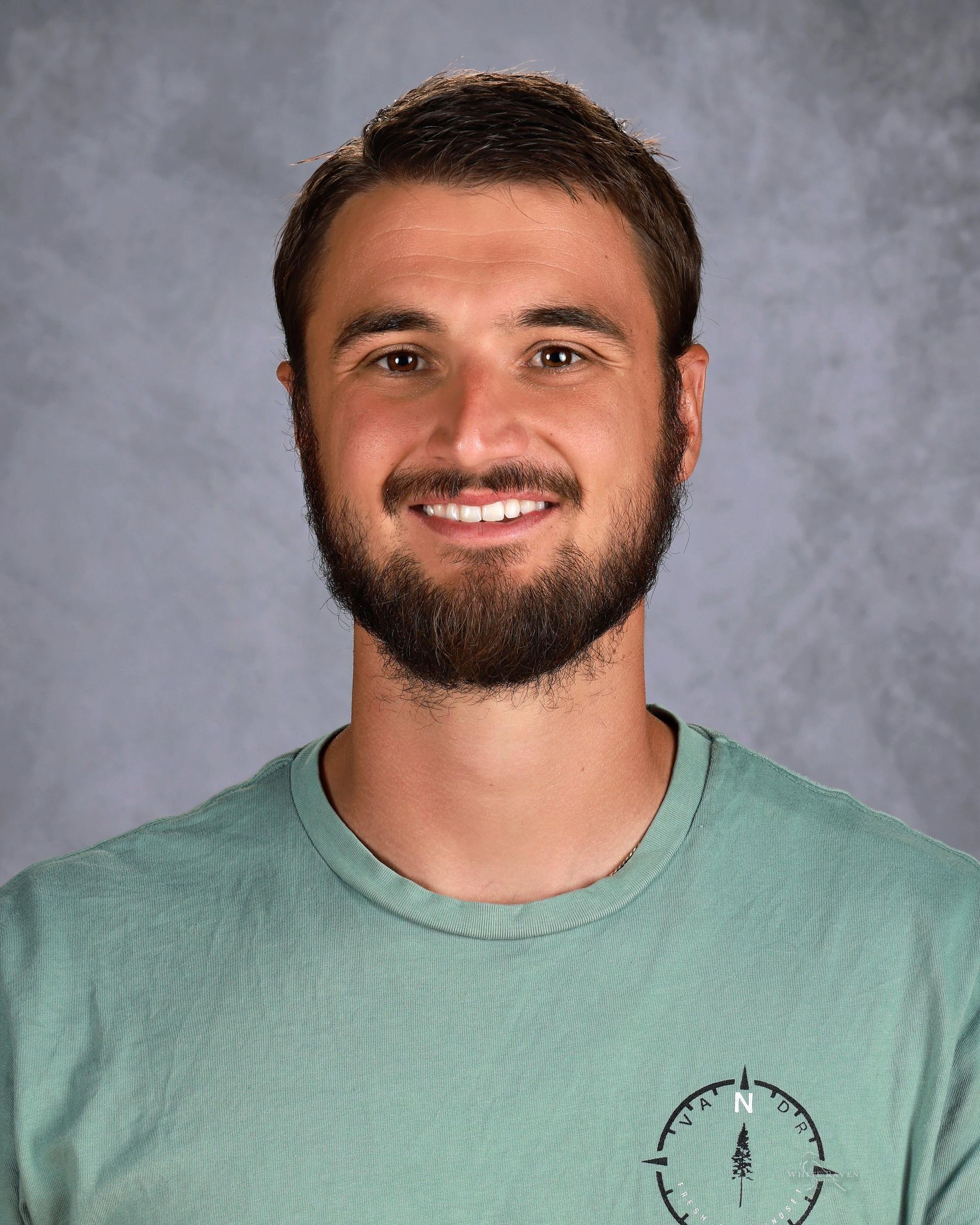 Smiling man with a beard wearing a light blue shirt.