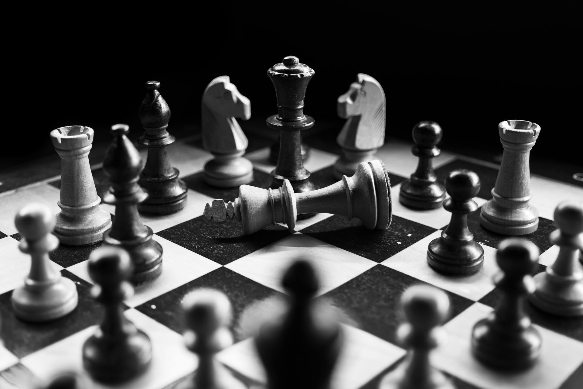 A black and white photo of a chess board with pieces on it.