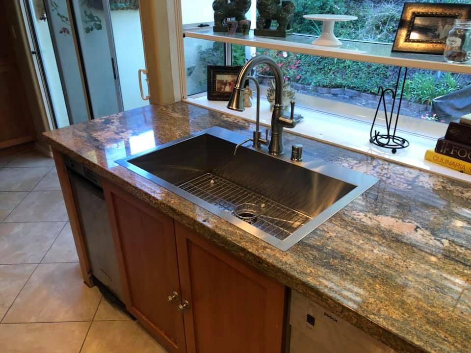 A kitchen with a stainless steel sink and granite counter tops