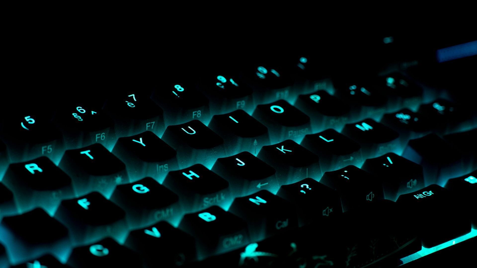 A close up of a computer keyboard with the letters glowing in the dark.
