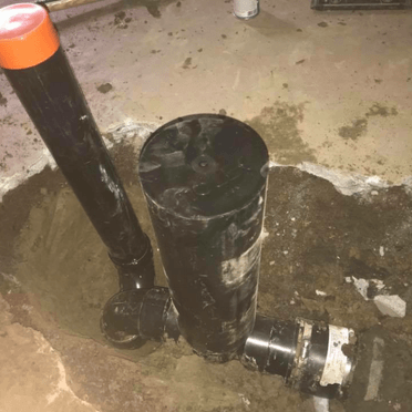 Un tuyau noir avec un bouchon orange repose dans la terre.