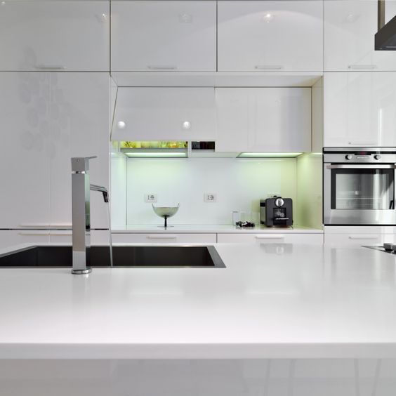 Une cuisine avec des armoires blanches et des appareils électroménagers en acier inoxydable