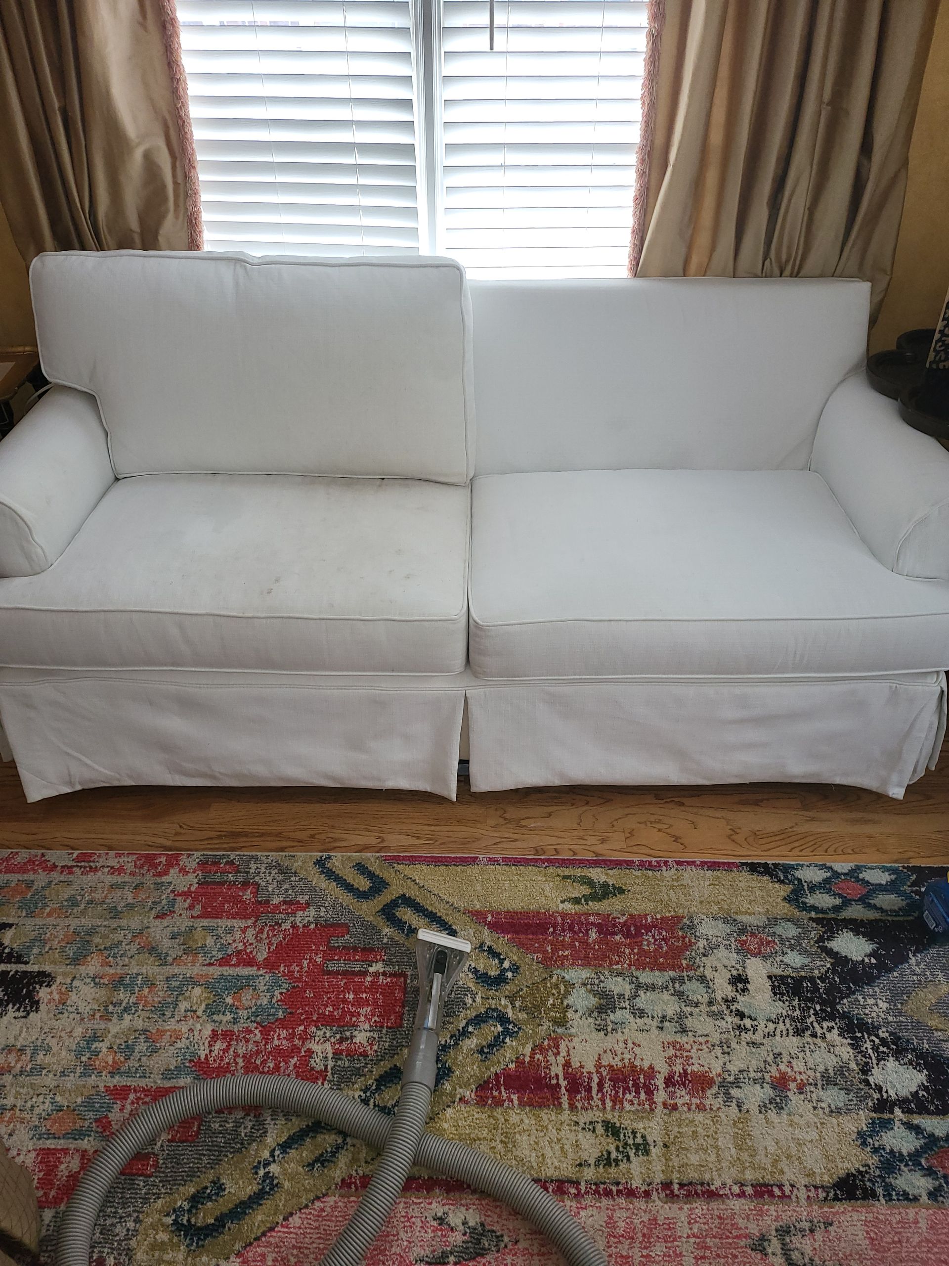 A white couch is sitting in a living room next to a rug.