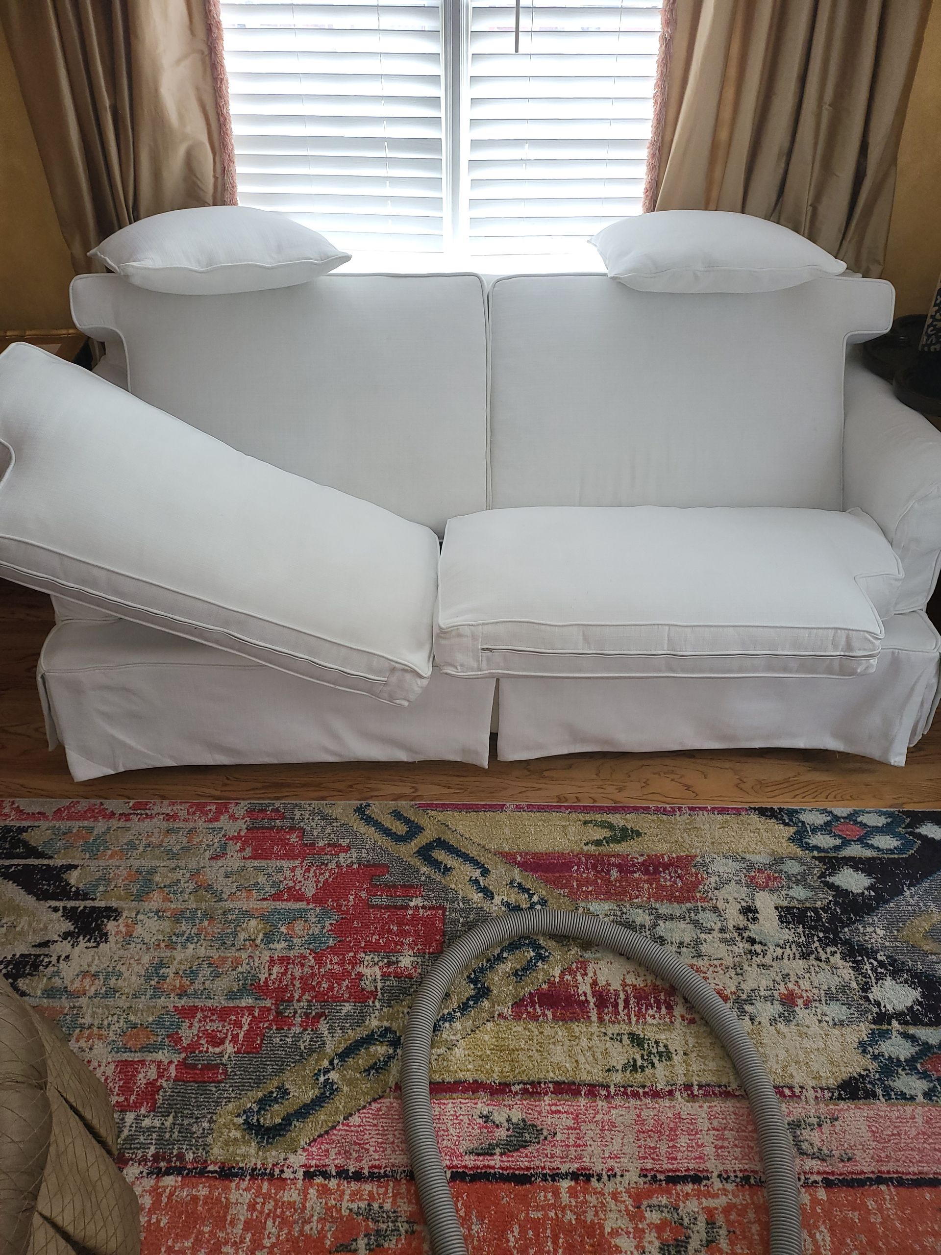 A white couch is sitting in a living room next to a rug.