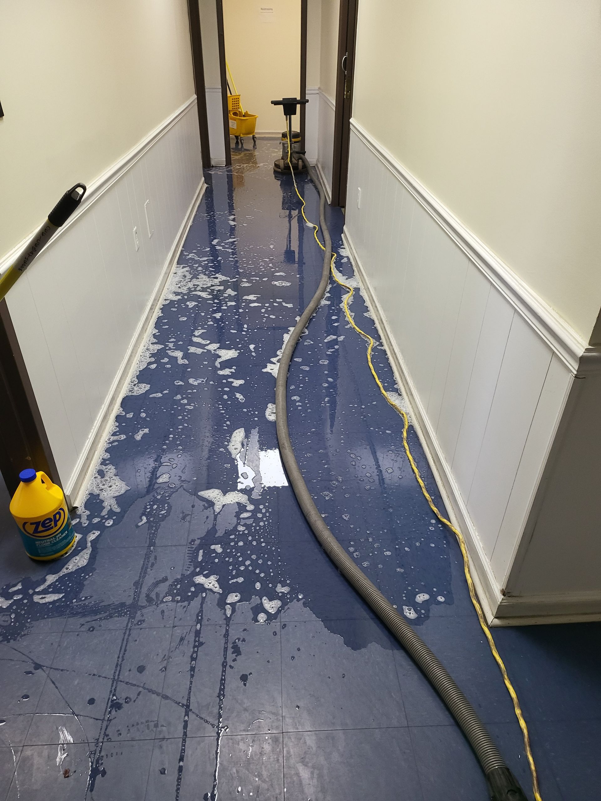 A hallway with a hose and a gallon of bleach