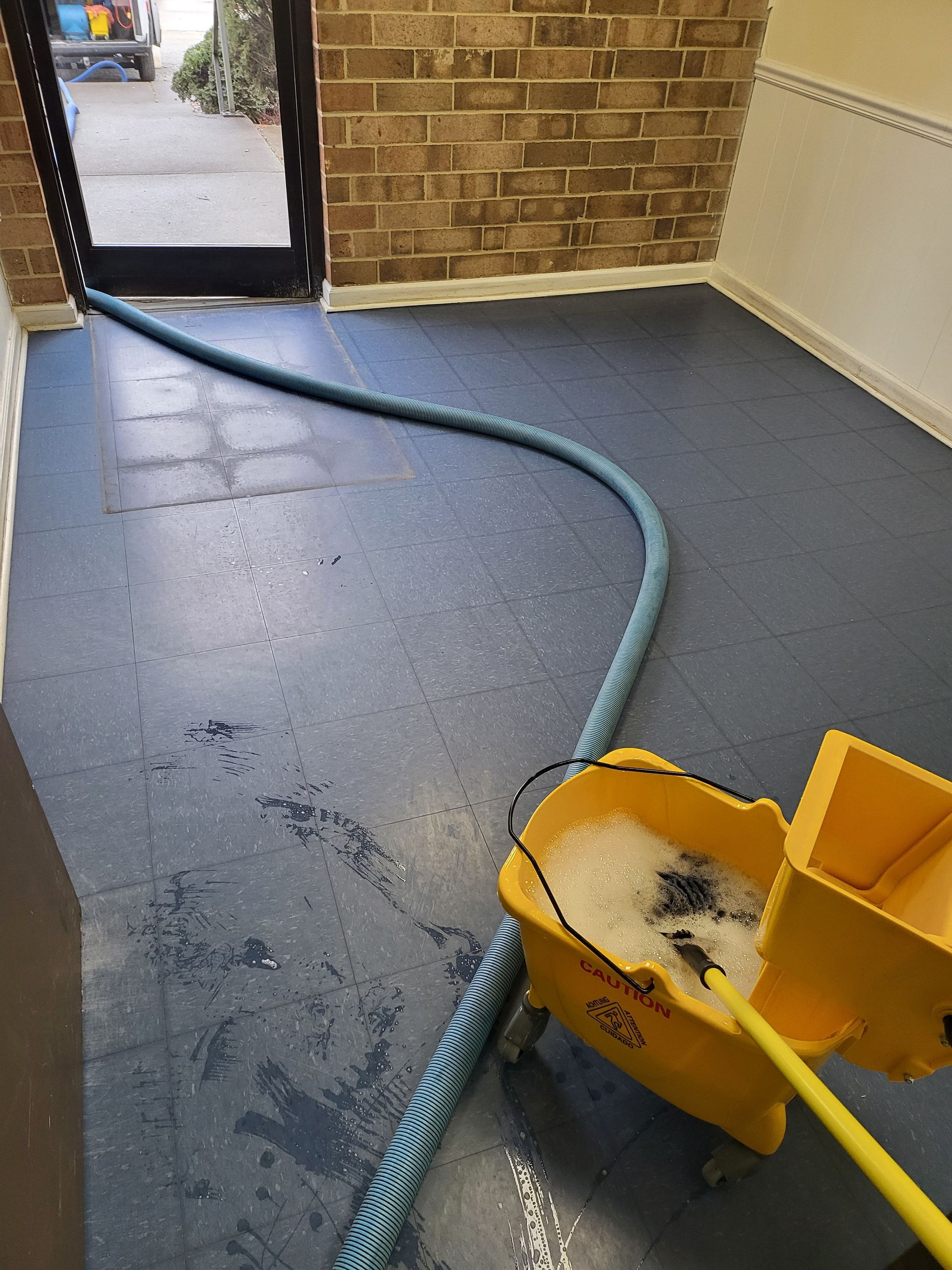 A yellow mop and bucket on a blue tiled floor