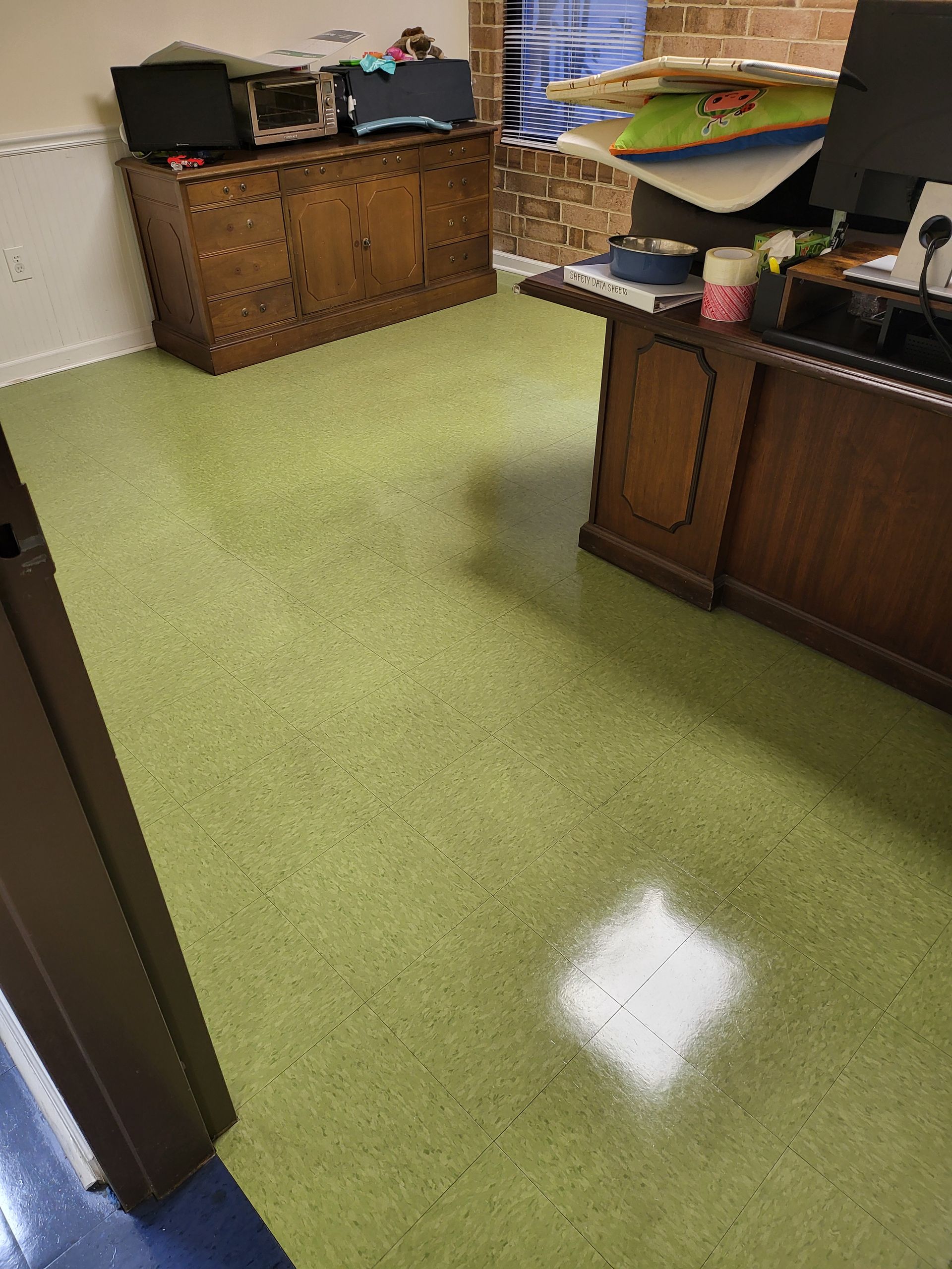 A room with a green carpet and a wooden desk