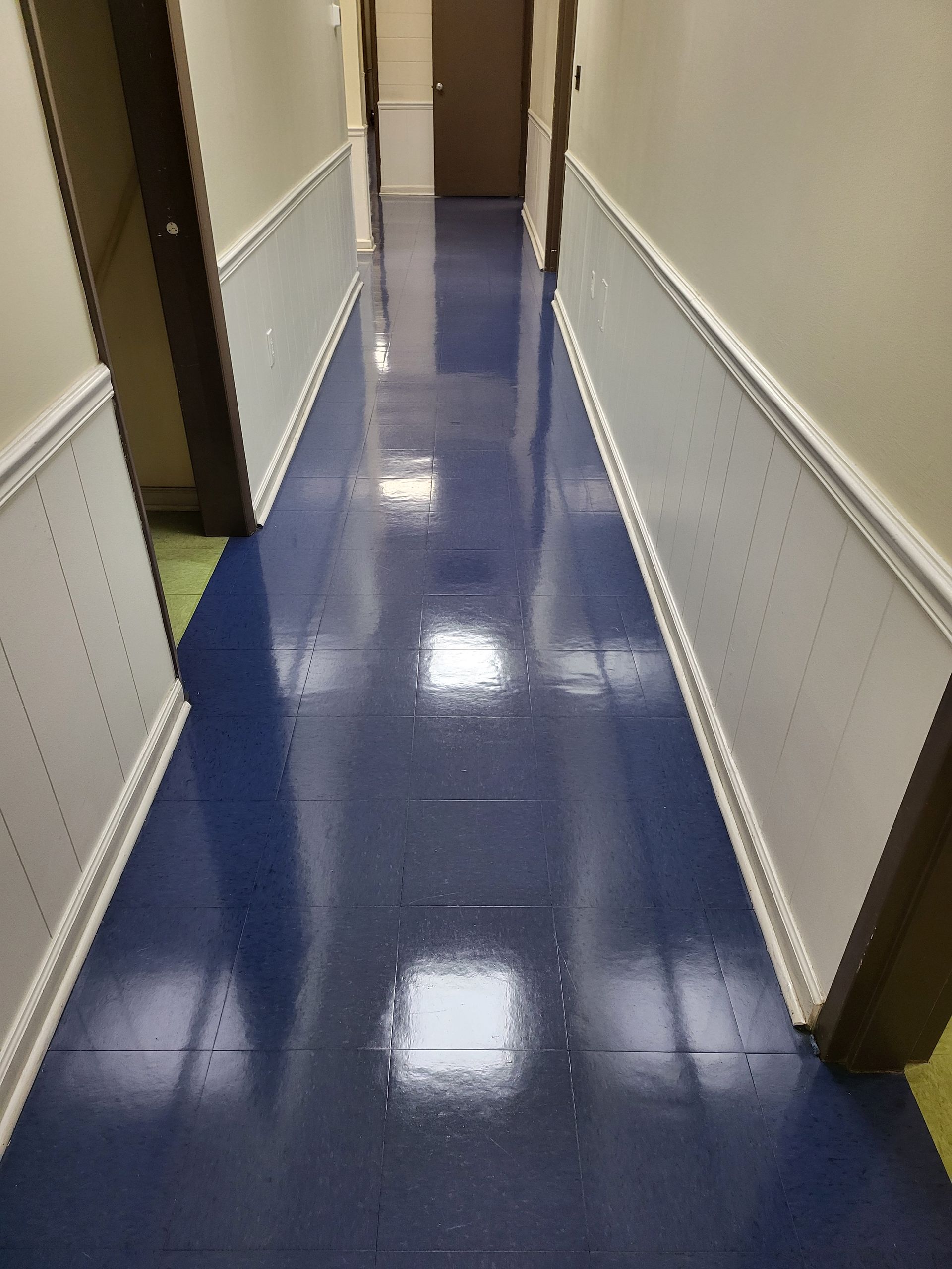 A hallway with blue tile floors and white trim.