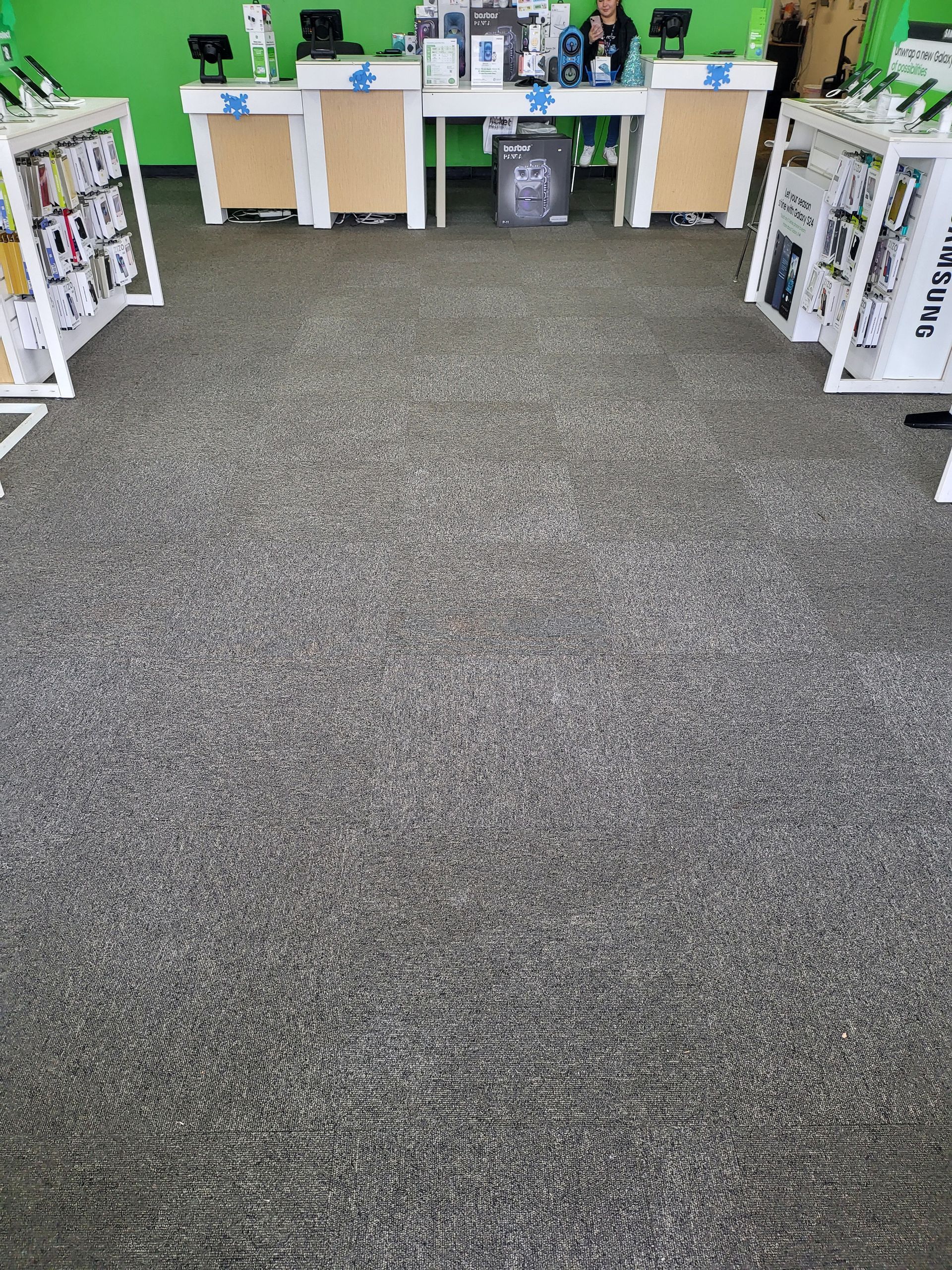 A gray carpeted floor in a store with tables and shelves.