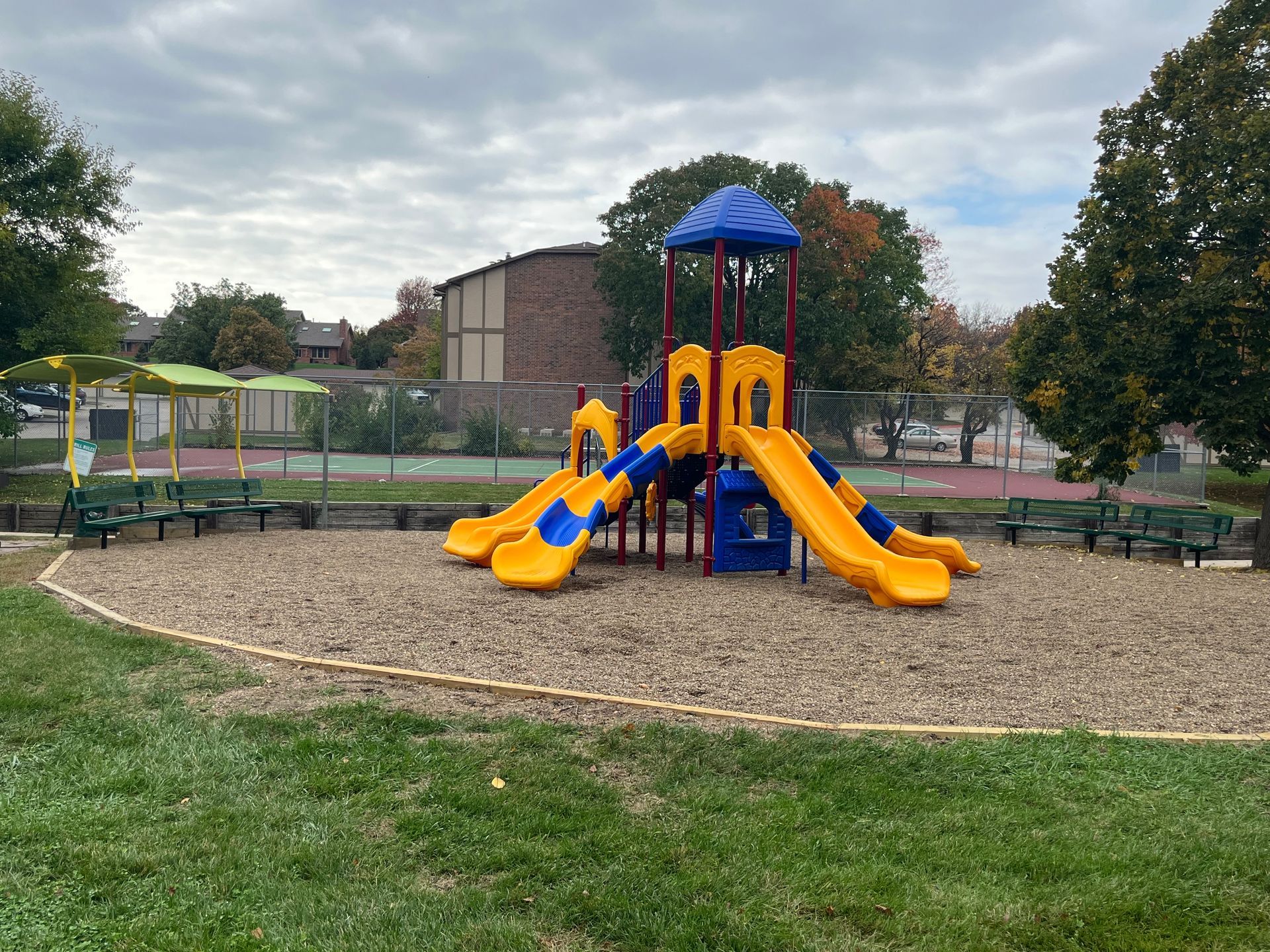 a colorful playground set in a park with trees in the background .