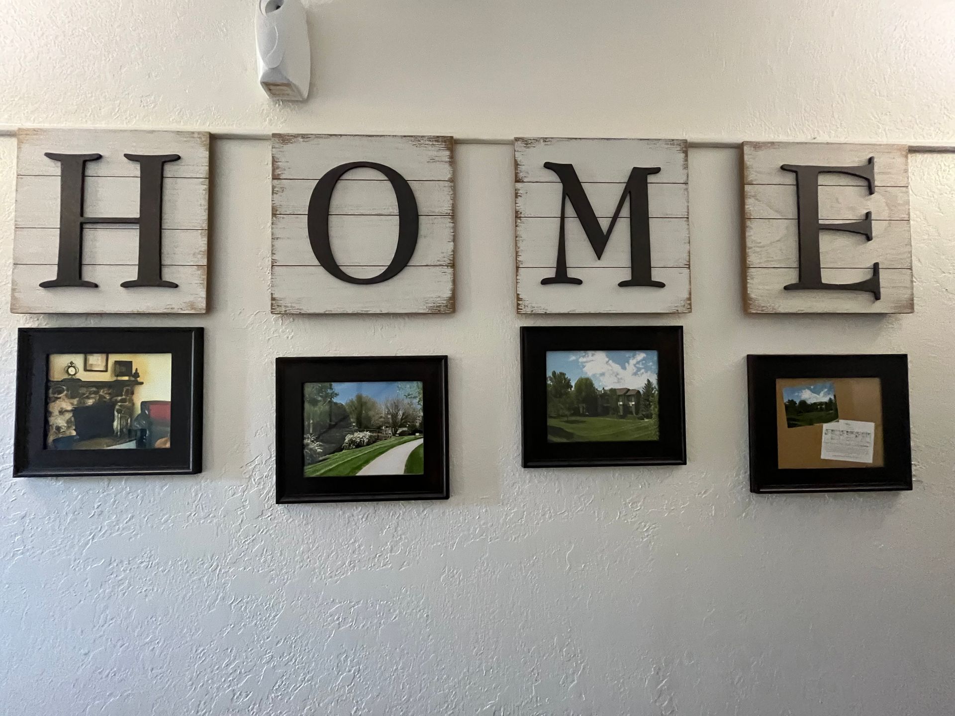 the word home is on a white wall surrounded by pictures