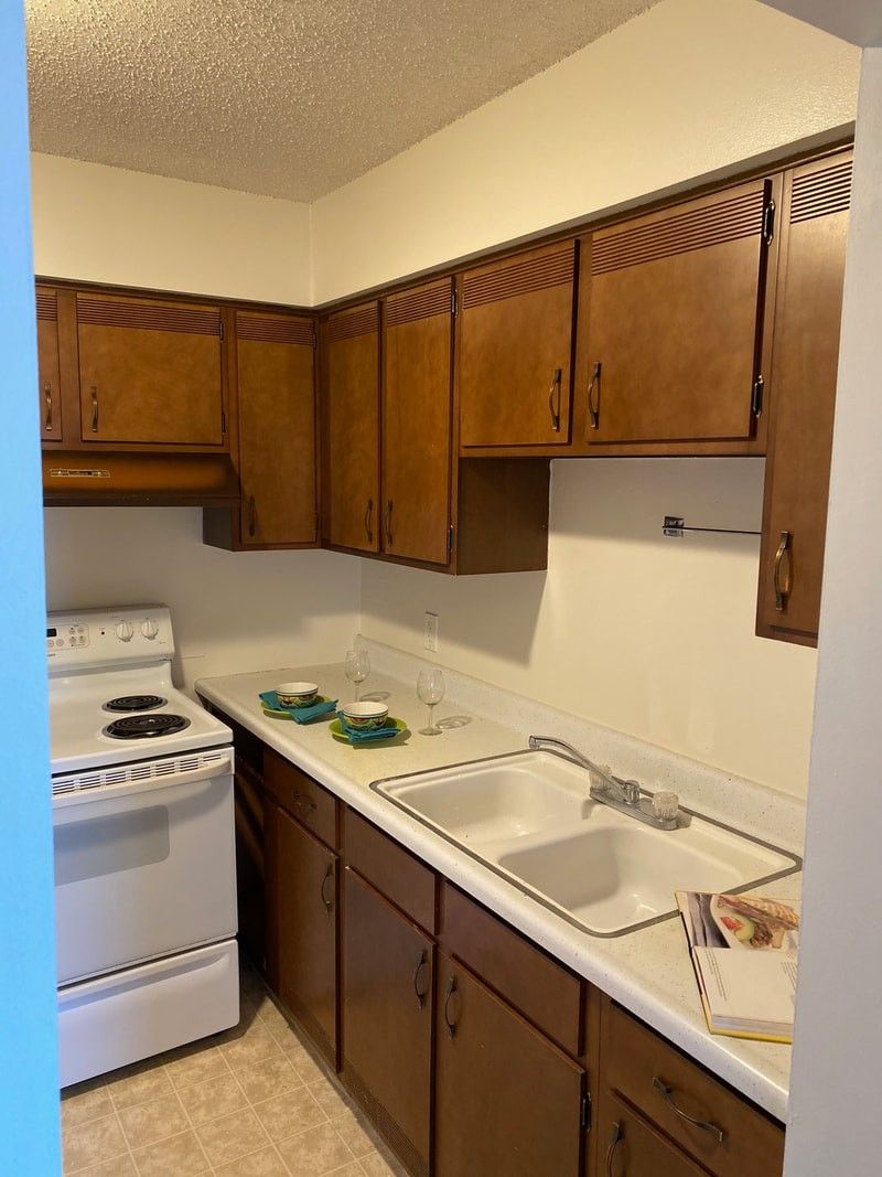 a kitchen with wooden cabinets , a sink , and a stove .